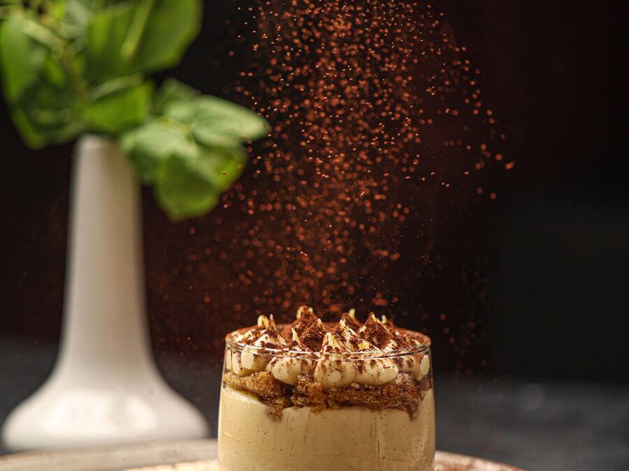A dessert with layers, a plate, and a flower in the background.