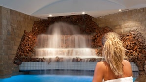 A person sitting by a pool with a waterfall feature.