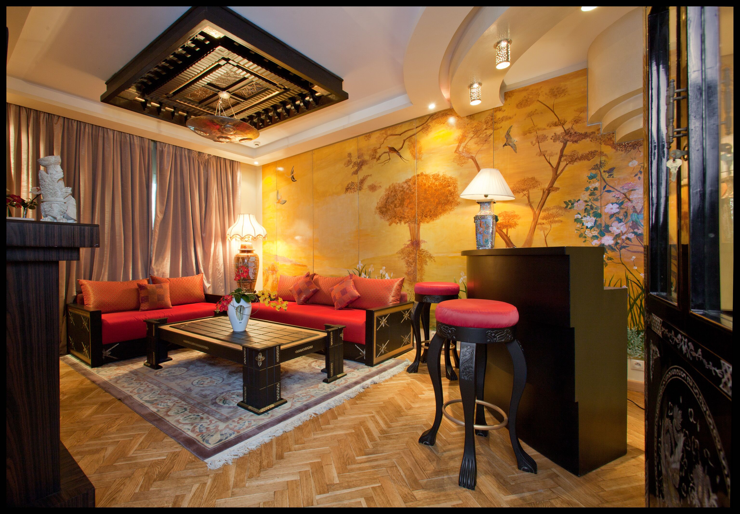Een woonkamer met een bank, een salontafel en een rode fauteuil, met decoratieve wand en een plafond met dakraam.