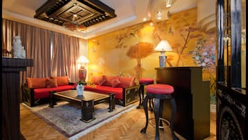 Een woonkamer met een bank, een salontafel en een rode fauteuil, met decoratieve wand en een plafond met dakraam.