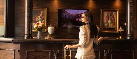 A reception desk with a television, framed artwork, and decorative vases.