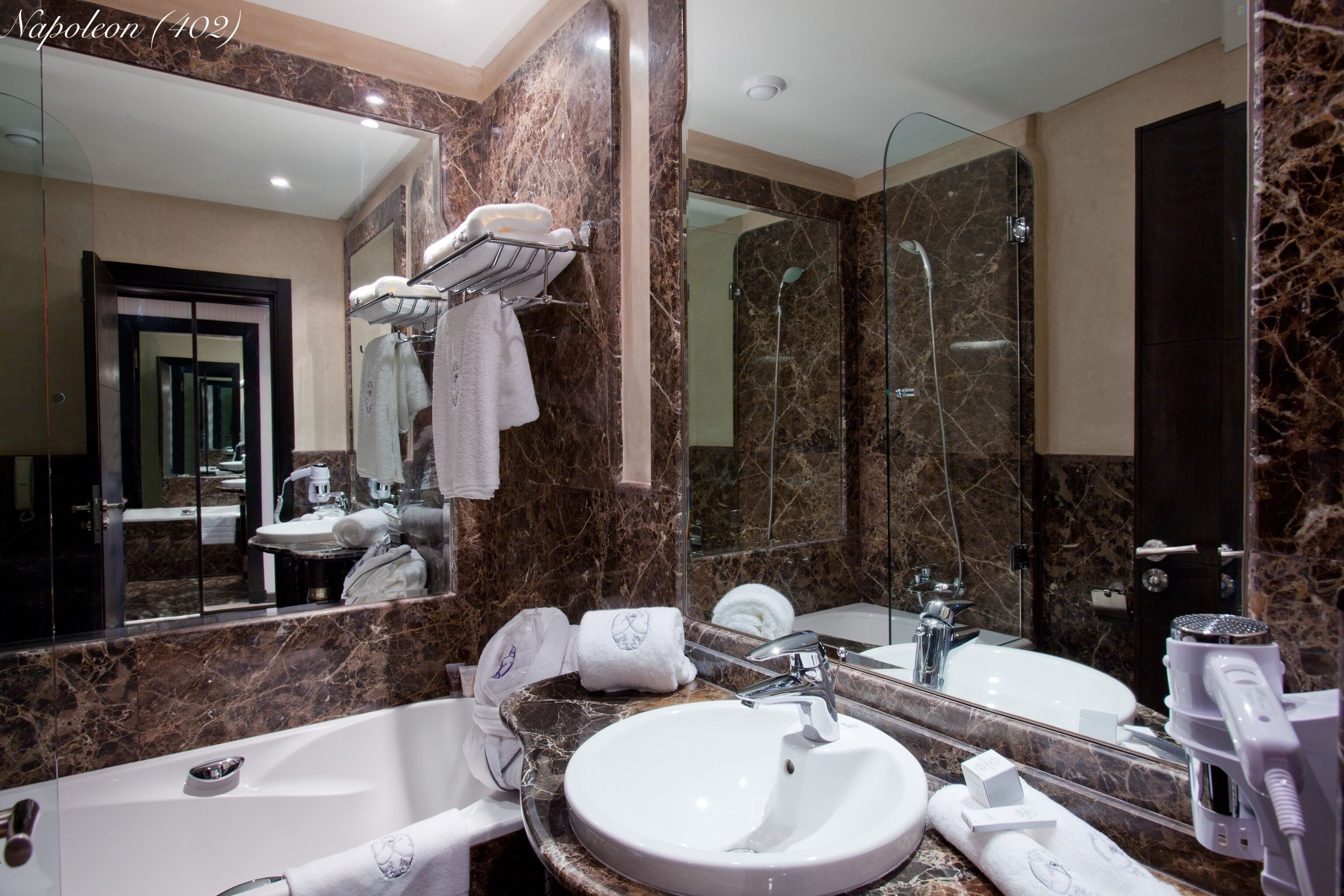 A modern bathroom with a marble vanity, a large mirror, a bathtub, and a shower area.