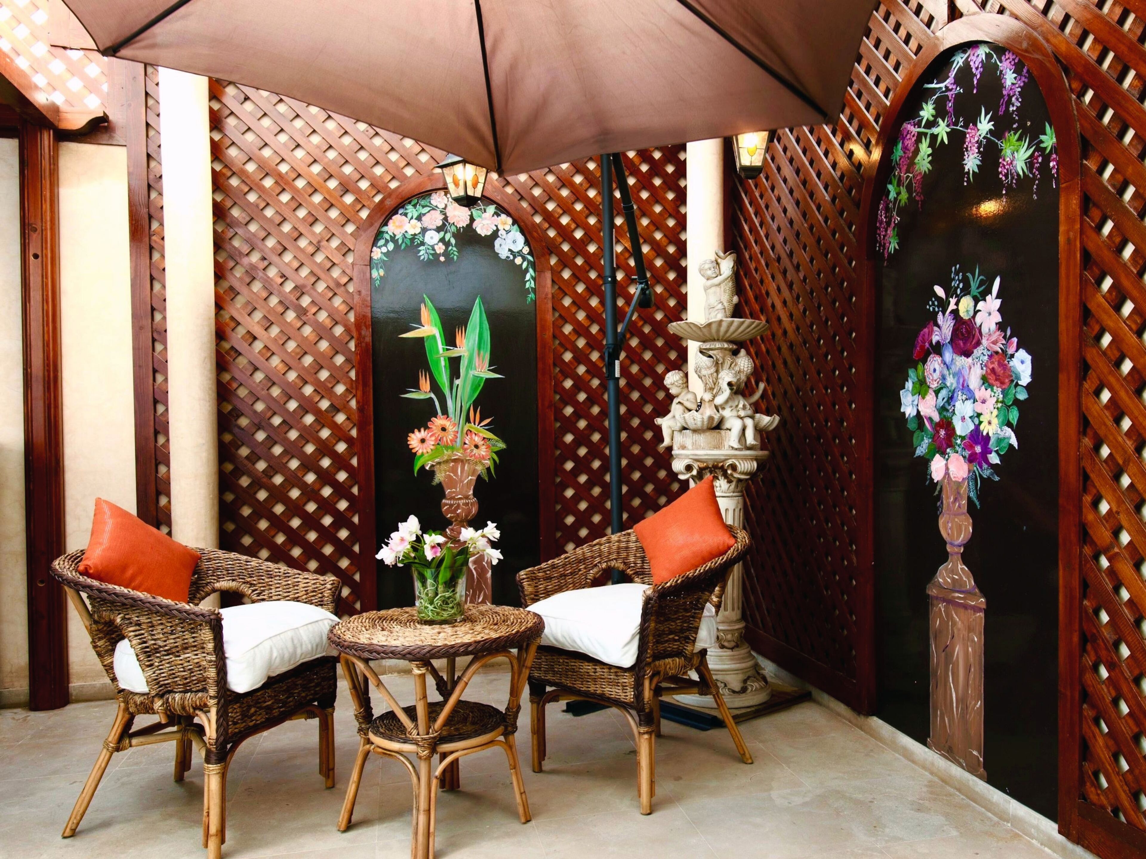 Une table en osier avec des chaises, un vase décoratif et une fontaine.