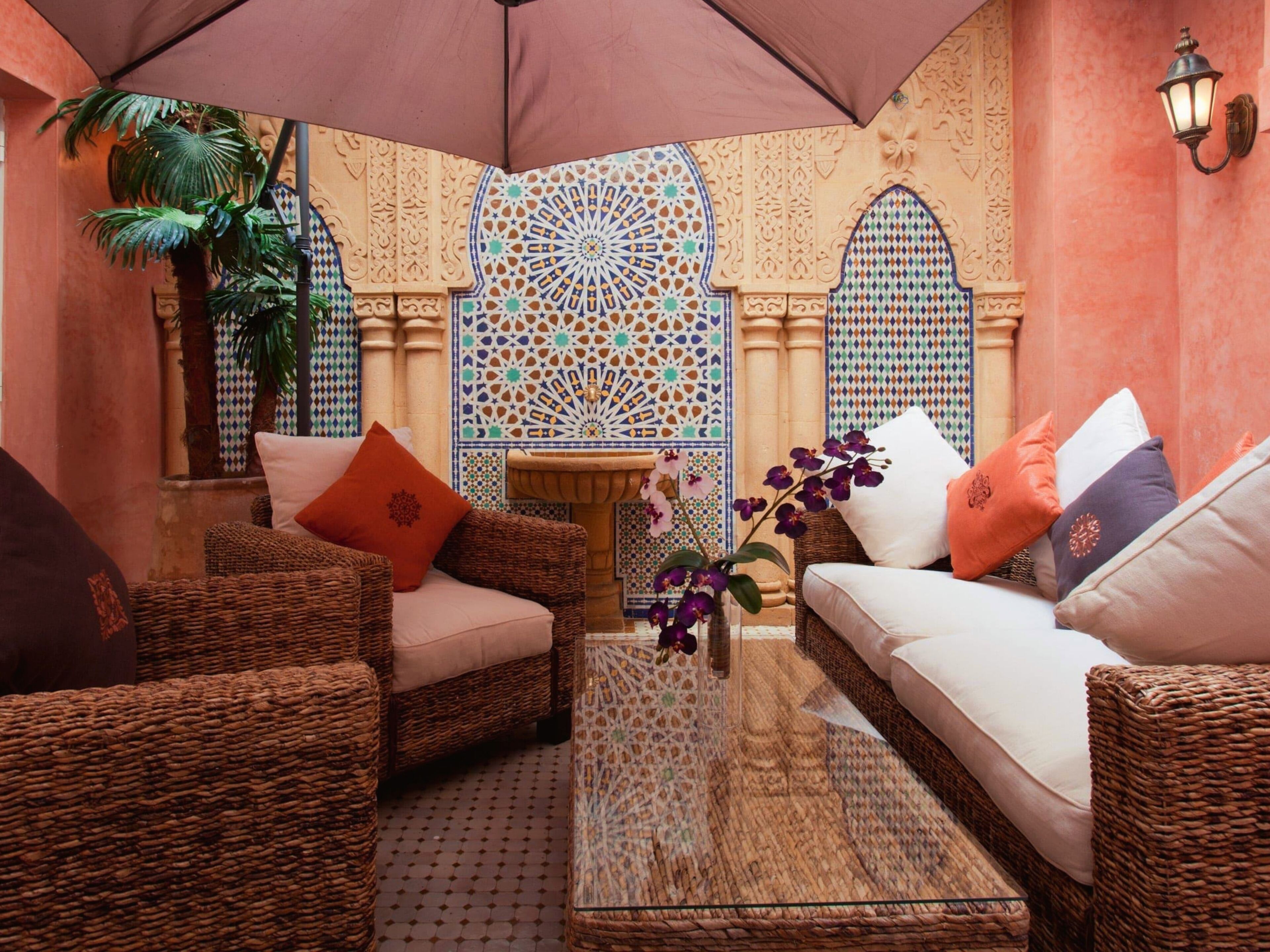 A cozy lounge area with wicker furniture, a glass-top coffee table, and a decorative tile wall.