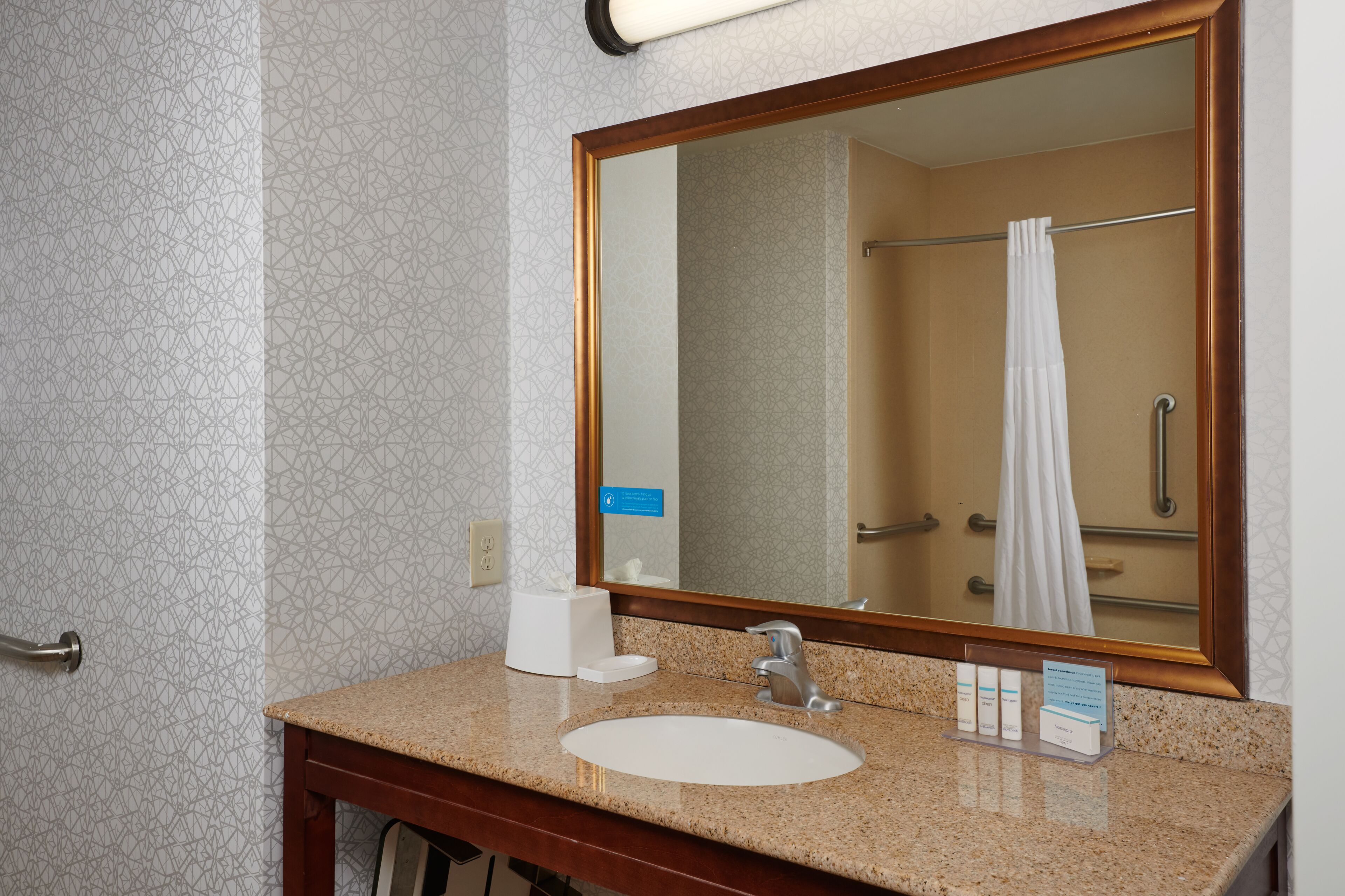 A bathroom with a sink, mirror, towel rack, and a shower curtain.