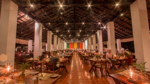 A spacious restaurant with high ceilings and wooden beams, featuring long communal tables and individual seating. - Sigiriya Village (Sigiriya)