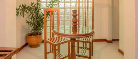 Un coin repas avec une table et des chaises en bois, un luminaire suspendu et une plante en pot.
