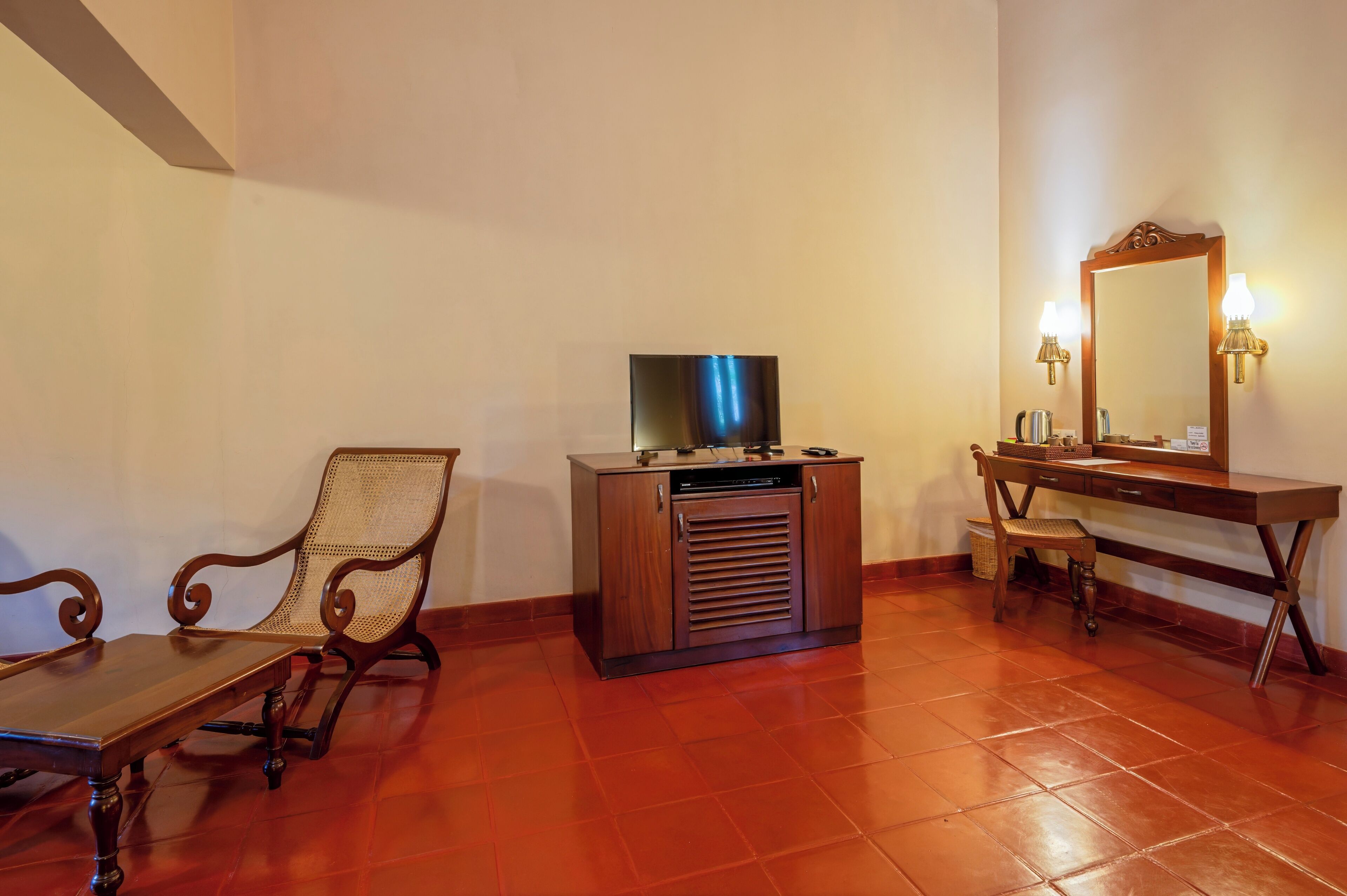 A room with a wooden cabinet, a television, a chair, a desk, and a mirror.