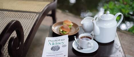 A table with a book titled "The Psychology of Money," a teapot, cups, and a plate with sandwiches.