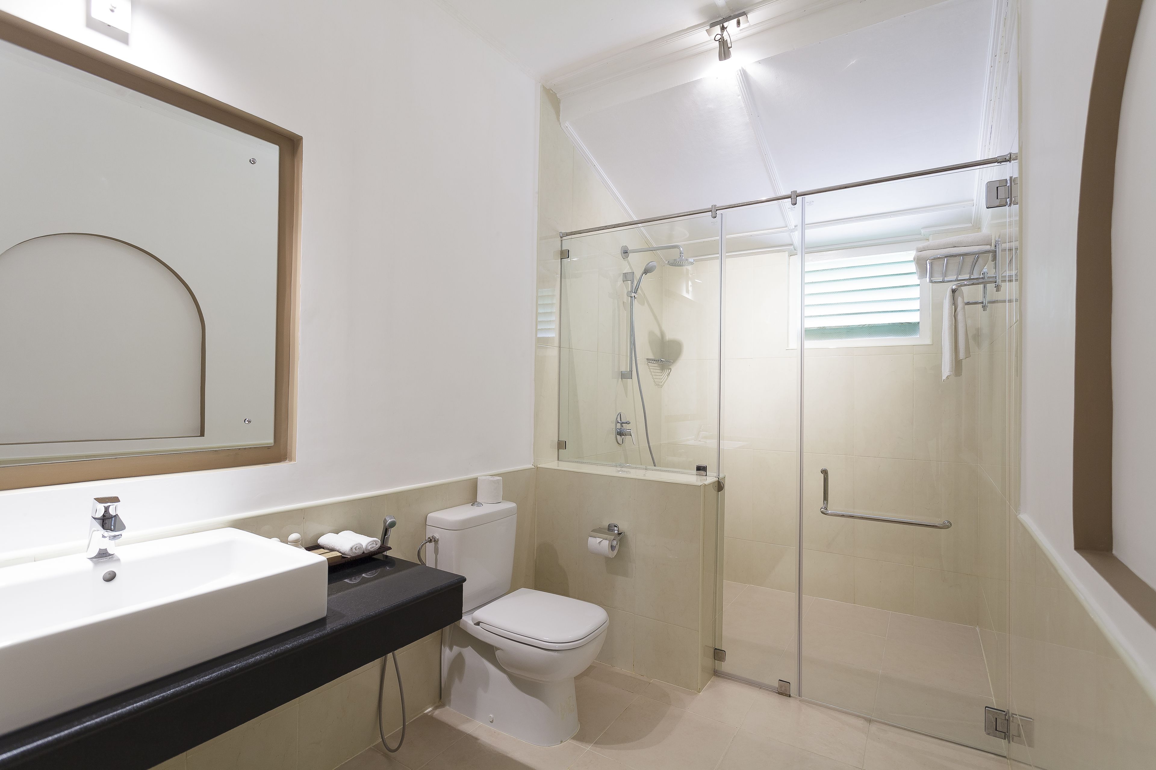 A modern bathroom with a glass-enclosed shower, a white sink, and a toilet.