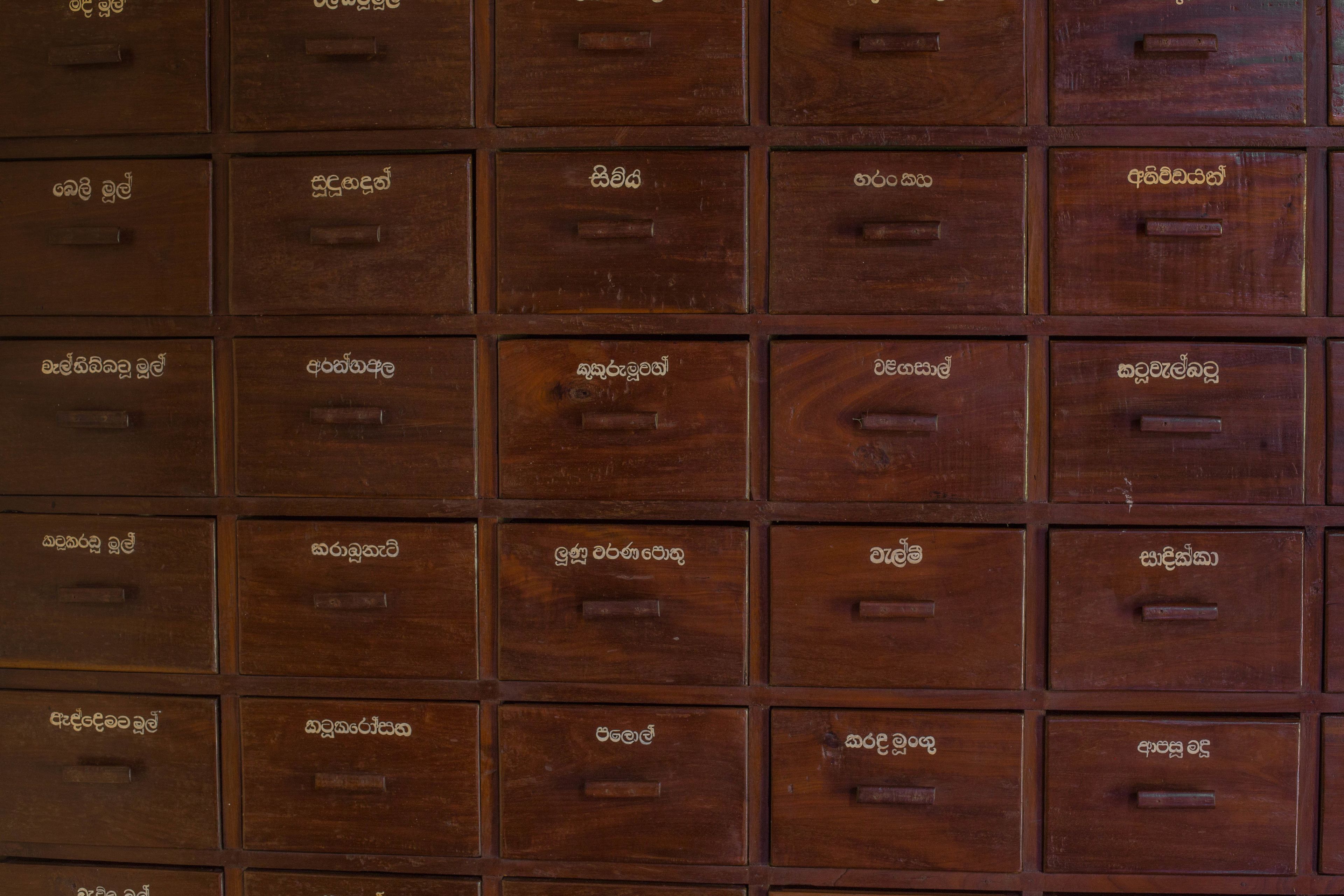 Un mur composé de boîtes de rangement en bois, chacune étant munie d’une étiquette.