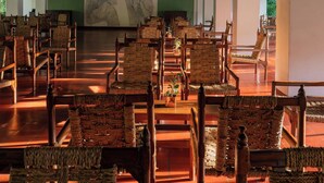 A spacious hall with rows of wooden chairs and a large mural on the wall. - Sigiriya Village (Sigiriya)