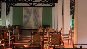 Un amplio salón con filas de sillas de madera y un gran mural en la pared.