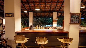A bar area with wicker chairs, a bar counter, and a sign indicating happy hour with a 2.0% discount on beverages.