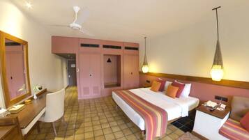 A hotel room with a bed, bedside table, chair, wardrobe, and a ceiling fan.