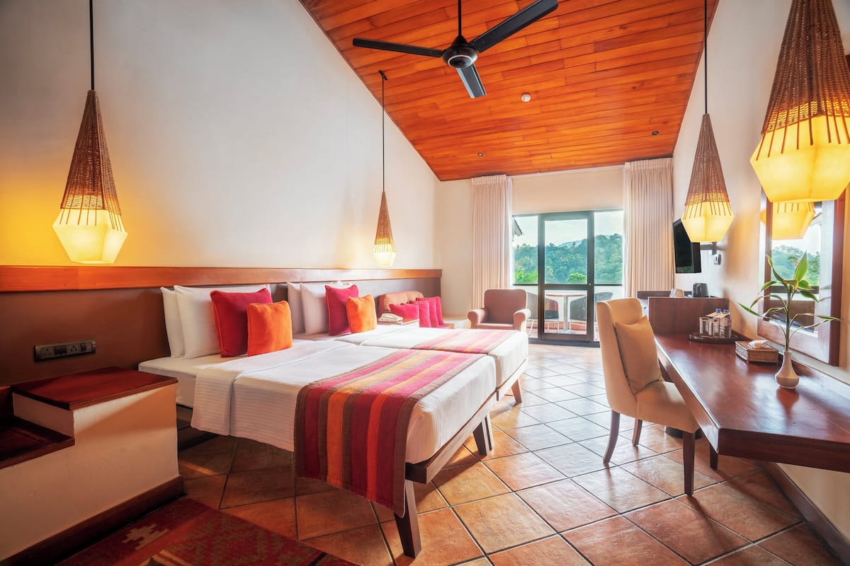 Une chambre d’hôtel avec un lit, deux chaises, un bureau et un balcon offrant une vue.