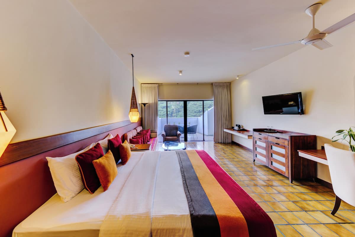 Une chambre d’hôtel avec un grand lit, un bureau, une télévision et un balcon avec vue.