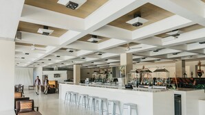 A spacious bar area with a long counter and multiple stools, a seating area with tables and chairs, and a high ceiling with exposed beams. - Cinnamon Citadel Kandy (Kandy)