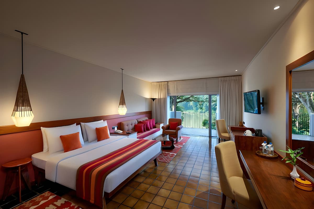 Une chambre d’hôtel avec un grand lit, un bureau, une chaise, une télévision et un balcon avec vue.