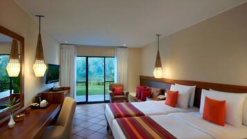 A hotel room with two beds, a desk, a chair, a TV, and a balcony with a view of the outdoors.