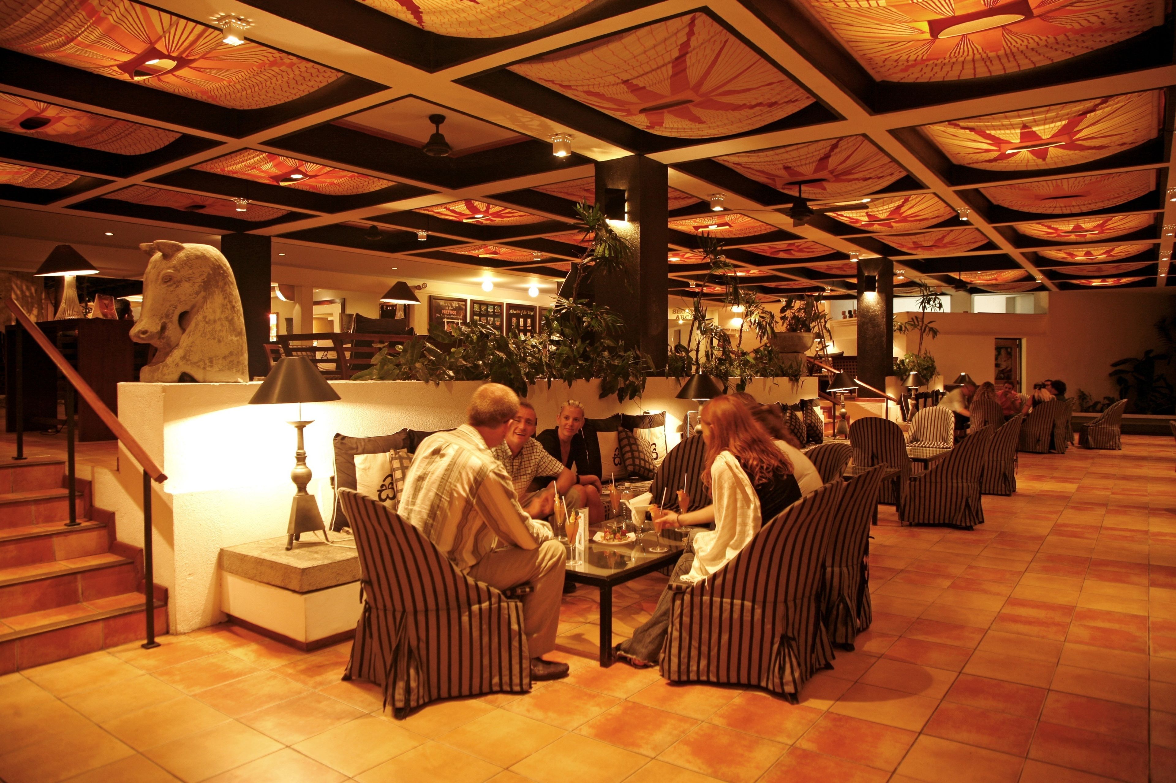 A spacious lobby with a high ceiling, a central staircase, and a seating area with striped chairs.