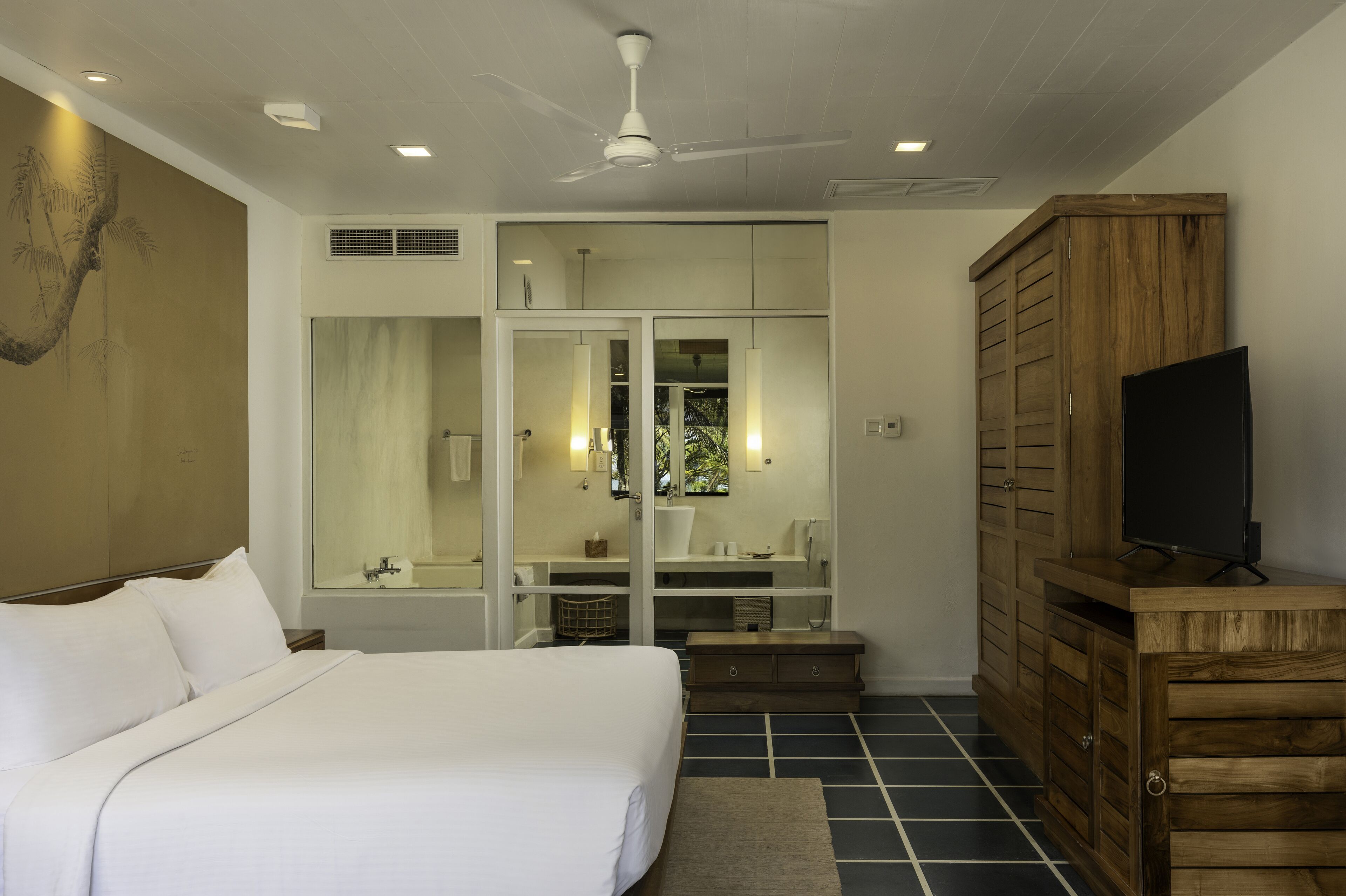 A bedroom with a bed, a wardrobe, a television, and a ceiling fan.