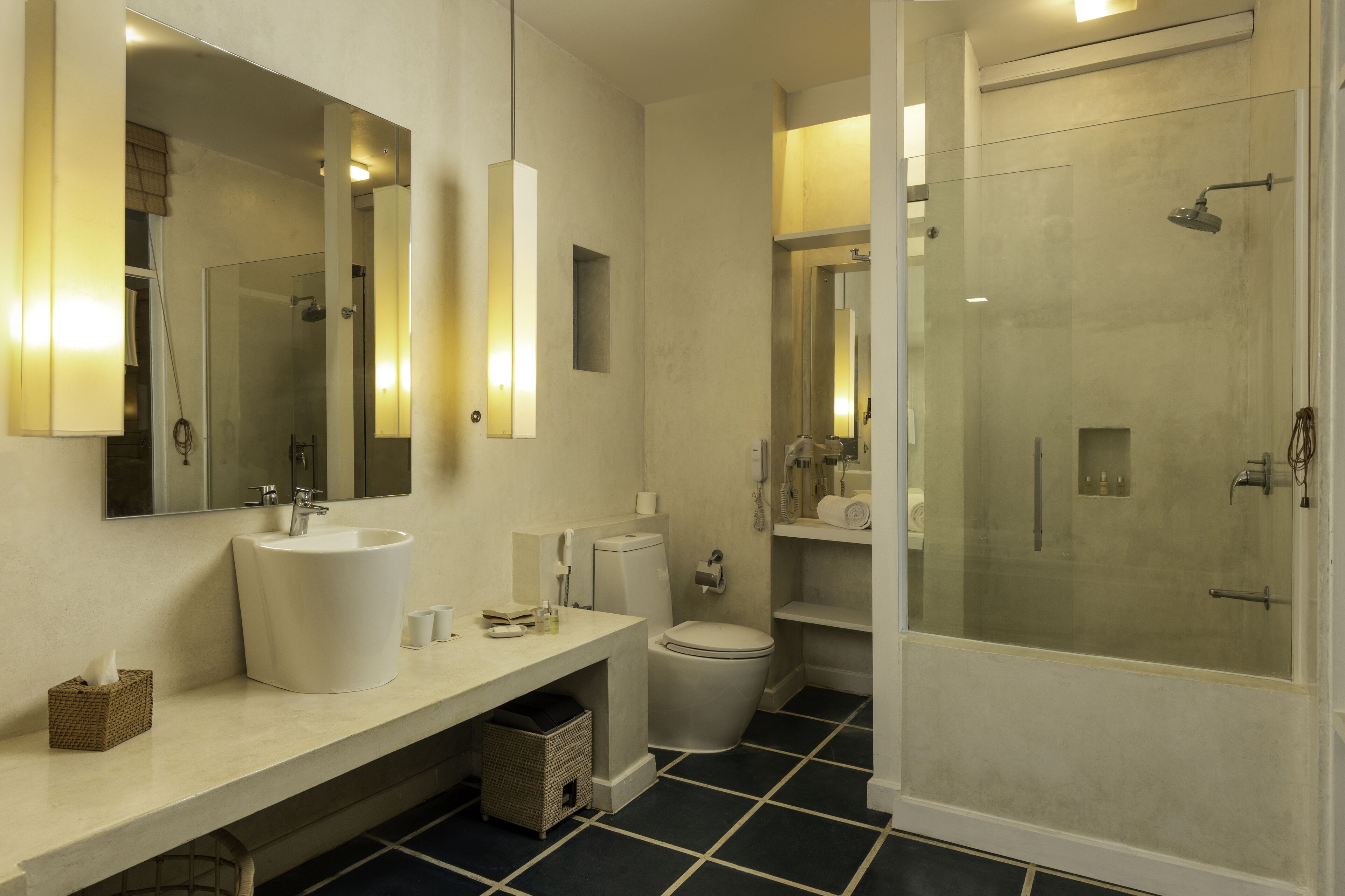 A modern bathroom with a large mirror, a sink, toilet, and a glass-enclosed shower.
