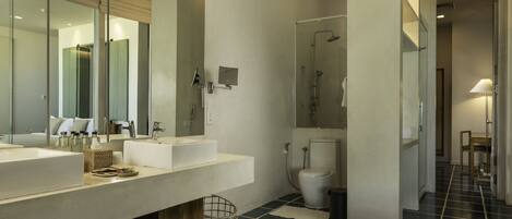 A modern bathroom with two sinks, a large mirror, and a shower area.