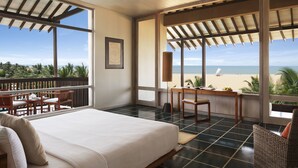 A bedroom with a bed, a desk, and a view of the beach.