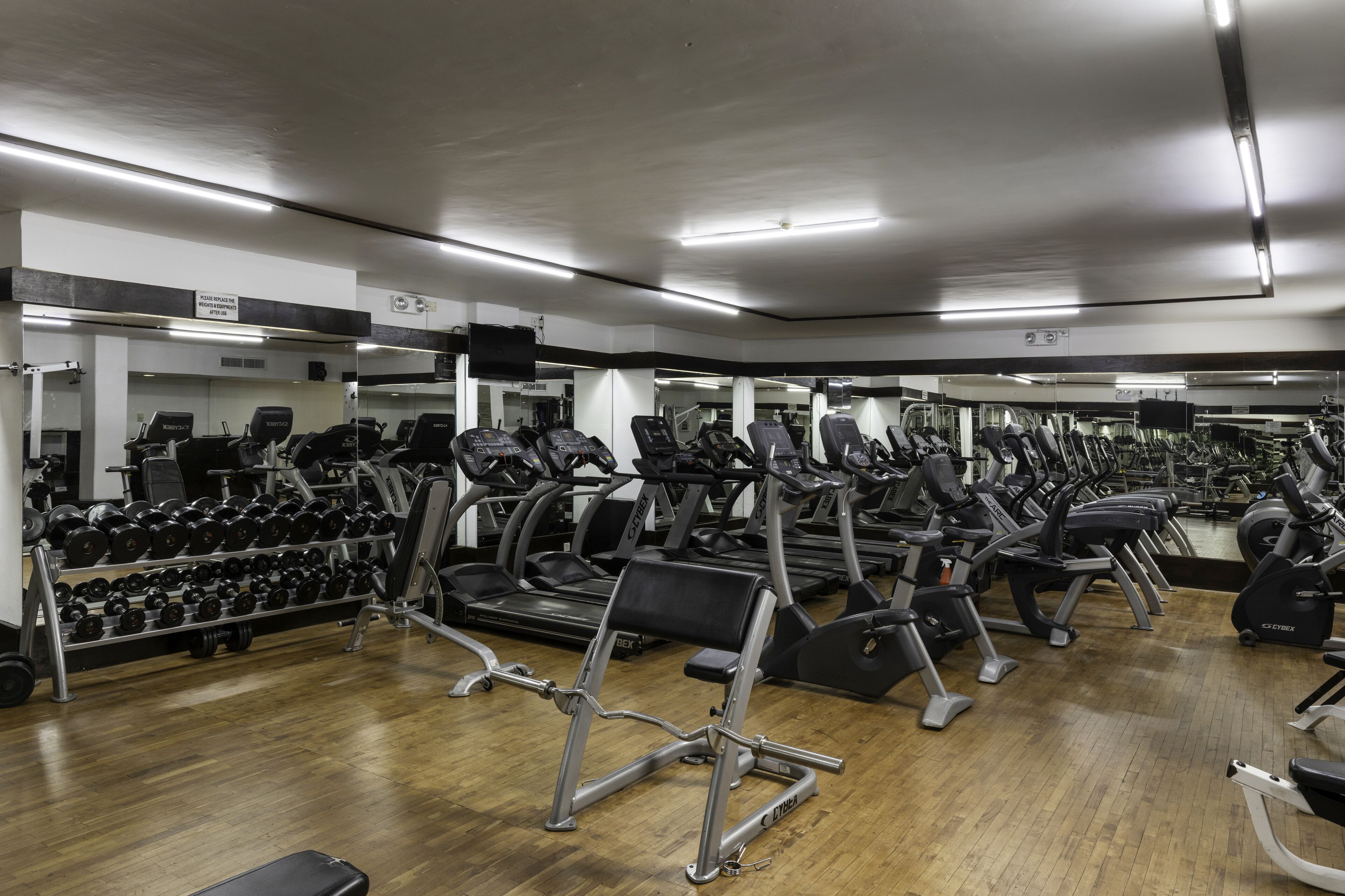 A gym with multiple treadmills, dumbbells, and weight machines.