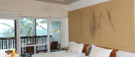 A hotel room with two beds, a balcony with a view of palm trees, a ceiling fan, and a large abstract painting on the wall.