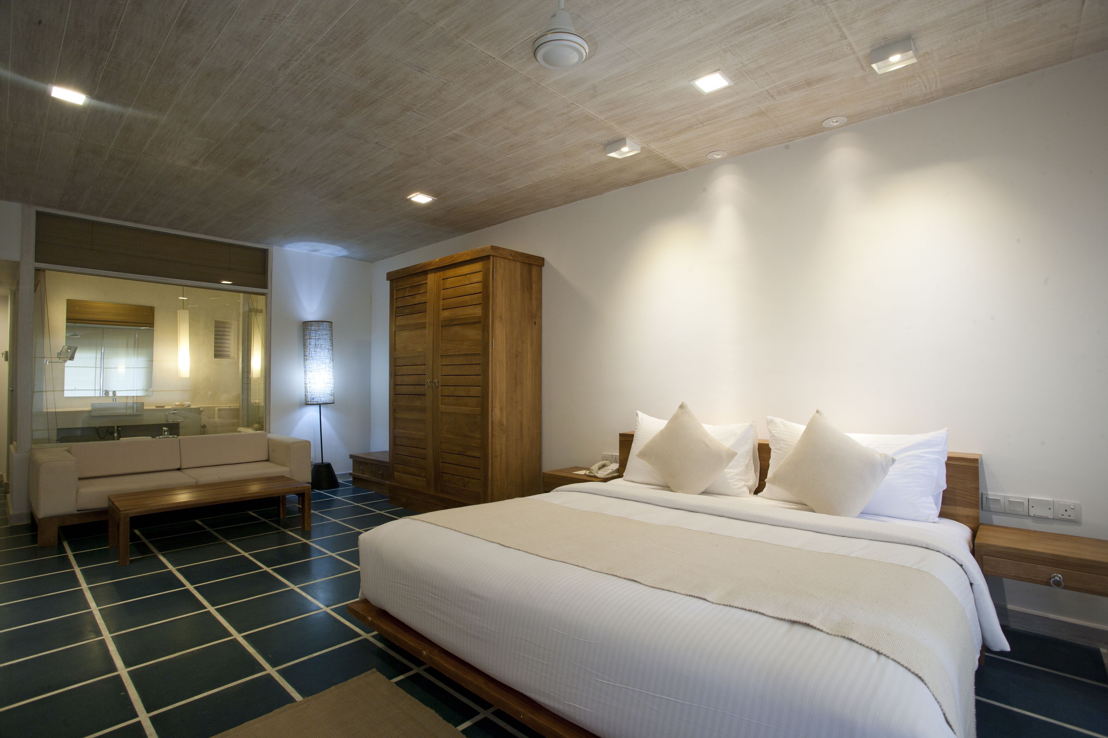 Un dormitorio con una cama grande, un armario de madera, un banco y un espejo.