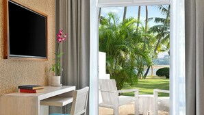 A modern room with a desk, chair, and a view of a tropical garden. - Avani Kalutara Resort (Kalutara)