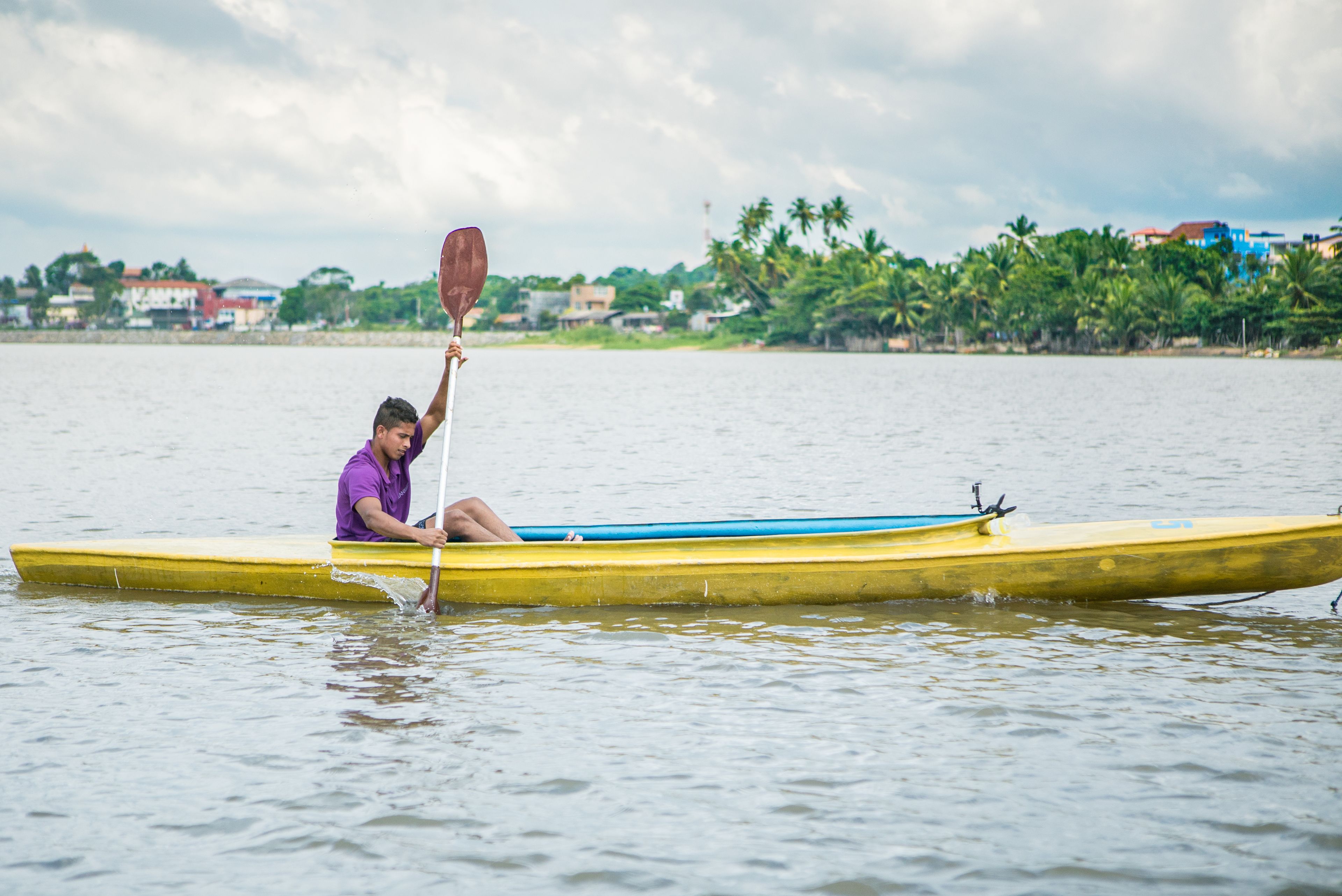 A person in a yellow canoe on calm water, holding a paddle.