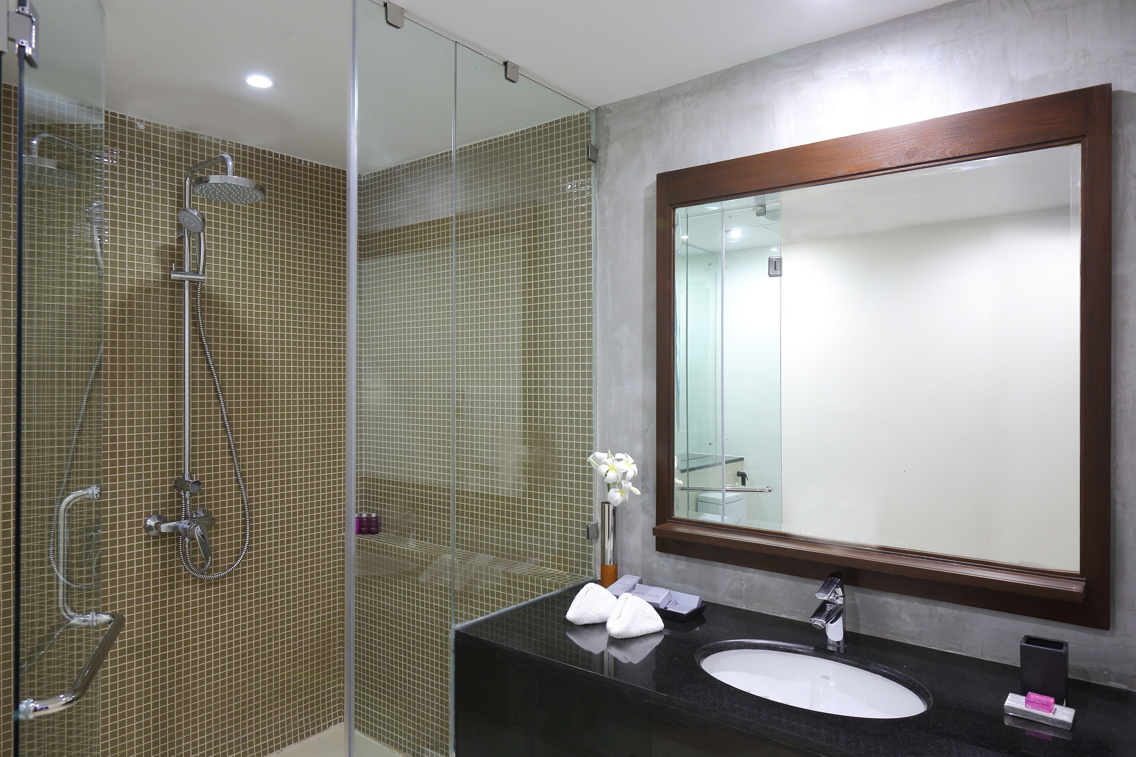 A bathroom with a glass-enclosed shower, a black sink, and a large mirror.