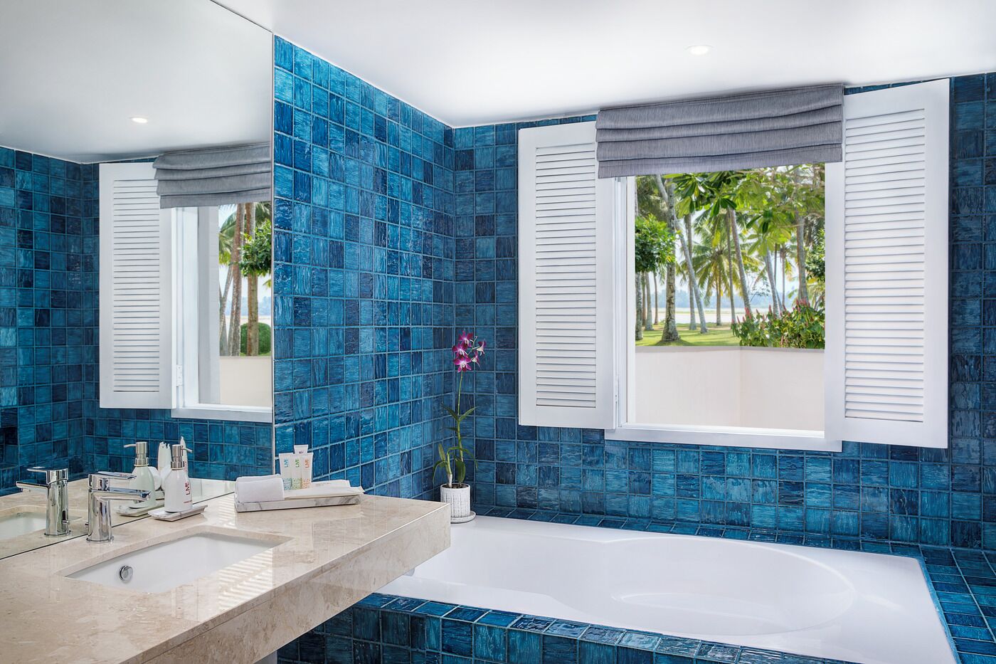 A bathroom with a bathtub, a sink, and a window with shutters.