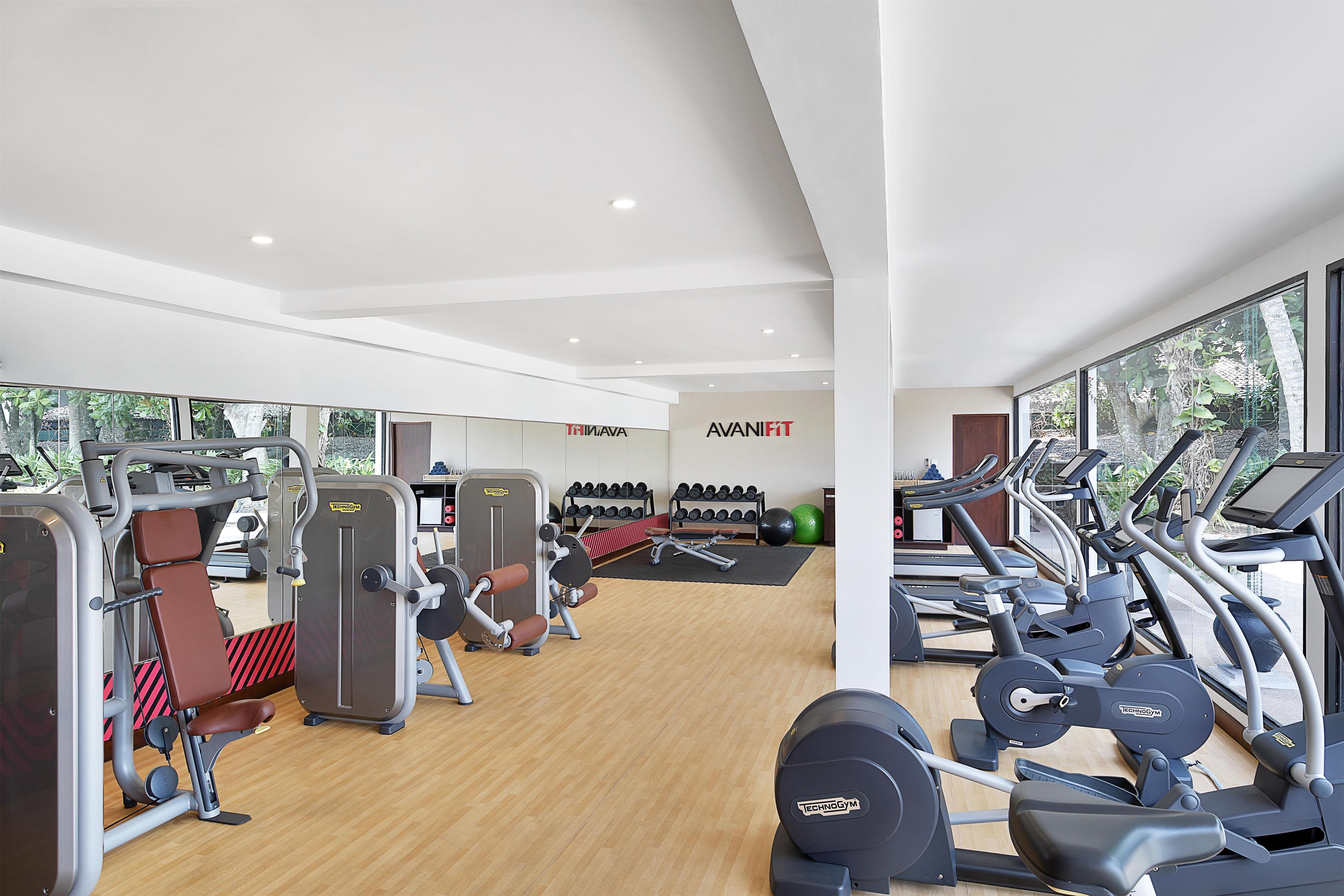 A gym with cardio machines, weightlifting equipment, and dumbbells.