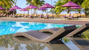 A poolside area with lounge chairs and purple umbrellas, surrounded by palm trees. - Avani Kalutara Resort (Kalutara)