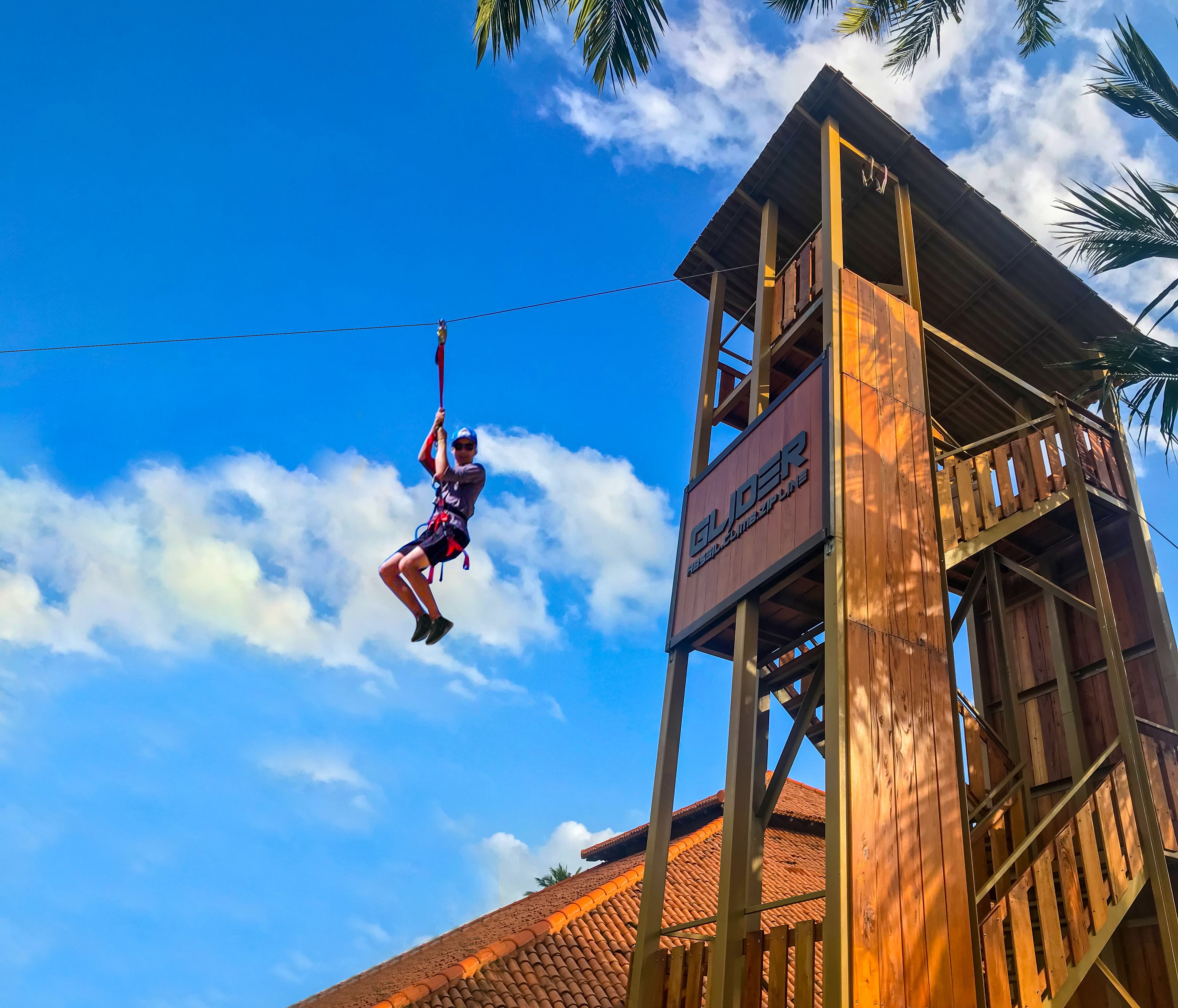 A zip-lining activity with a wooden tower structure and a clear blue sky.