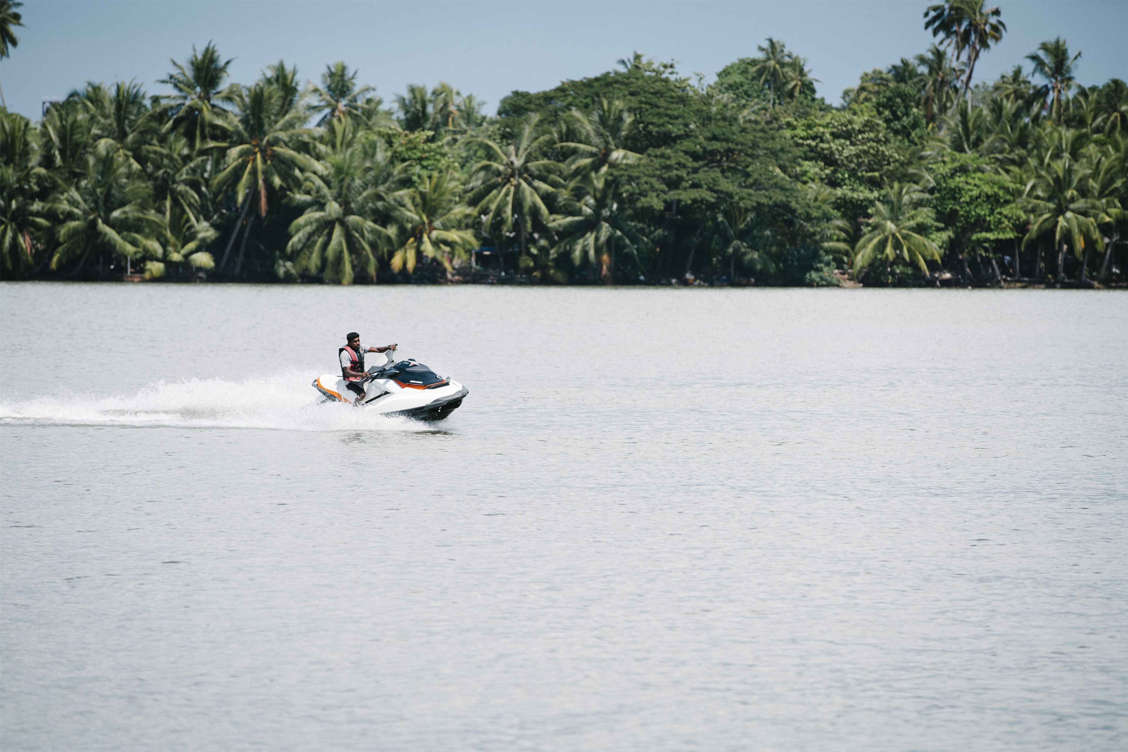 A person jet-skiing on a body of water with a backdrop of palm trees.