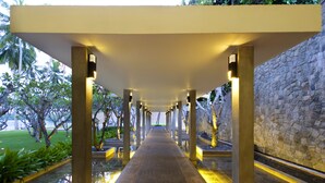A corridor with a stone wall on one side and a water feature on the other. - Avani Kalutara Resort (Kalutara)