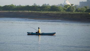 A person in a boat on a calm body of water with a distant structure.