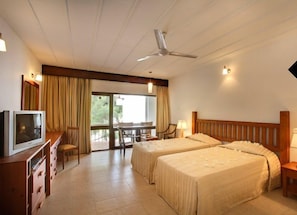 A hotel room with two beds, a TV, a desk, and a balcony with curtains. - Nilaveli Beach (Nilaveli)