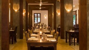 Una larga mesa de comedor dispuesta con sillas, un ventilador de techo e iluminación en la pared.