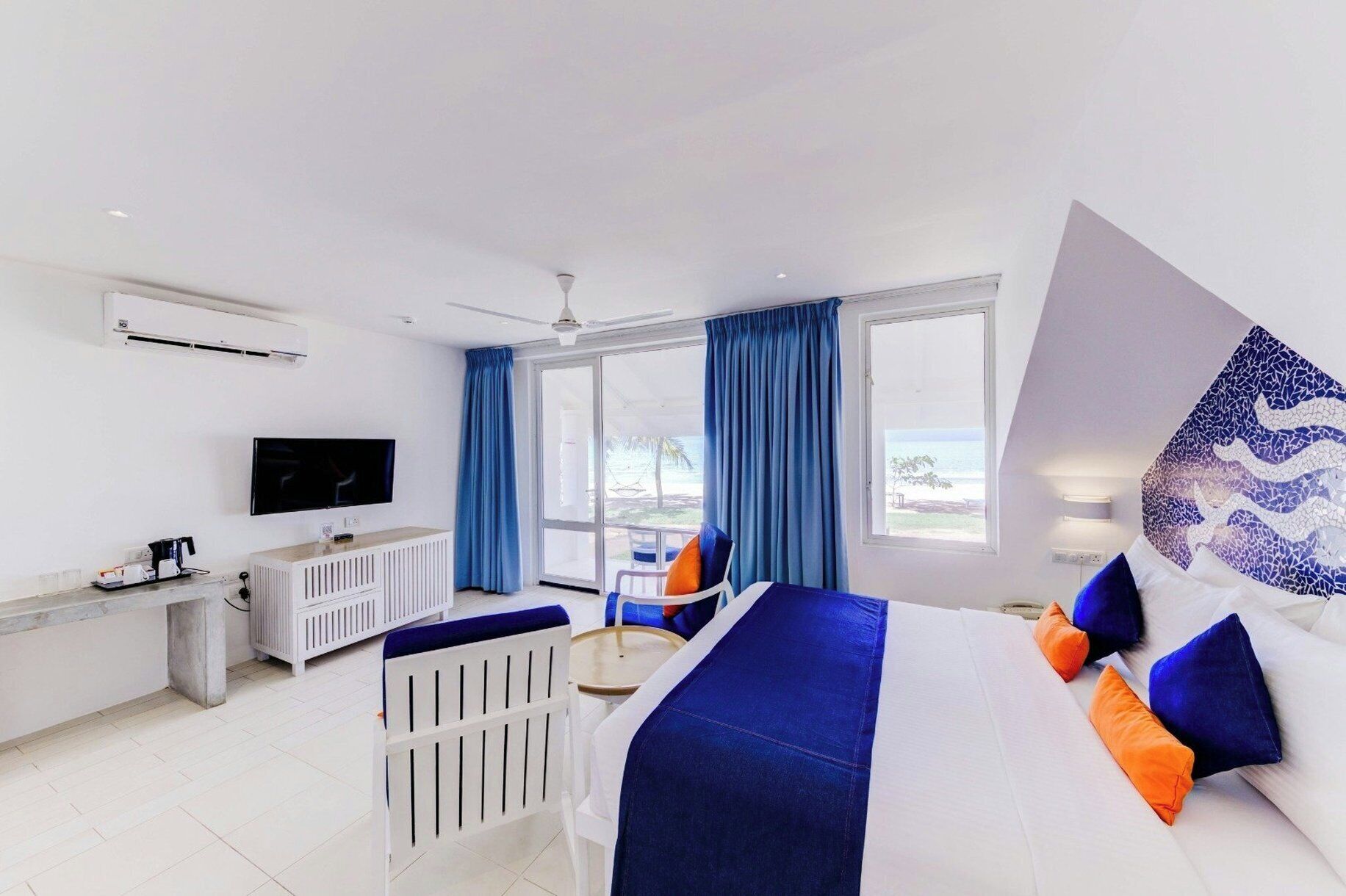 Ein Hotelzimmer mit Bett, Schreibtisch, Stuhl, Fernseher und Meerblick.