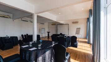 Une salle de conférence équipée de tables rondes, de chaises et d’un écran de projection.