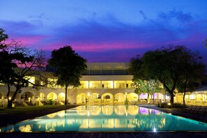 Guests can enjoy a refreshing swim in the hotel's large pool, surrounded by a paved walkway and stunning architecture.