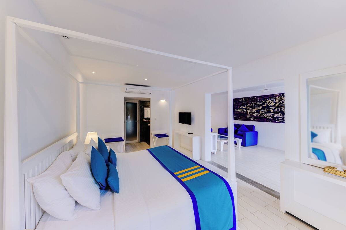 A modern hotel room with a large bed, a desk, a chair, and a TV.