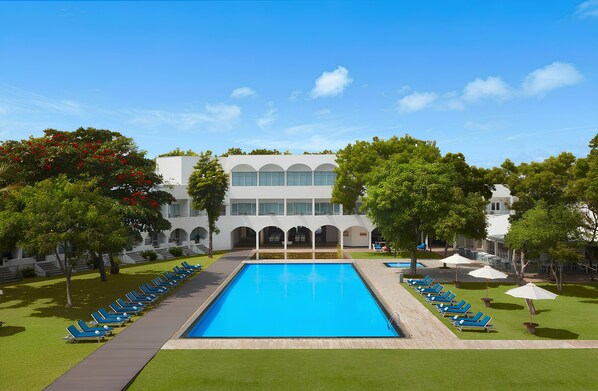 Relax by the resort's central pool surrounded by lounge chairs and lush greenery.