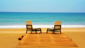 A wooden deck with two chairs facing the ocean. - Trinco Blu by Cinnamon (Trincomalee)